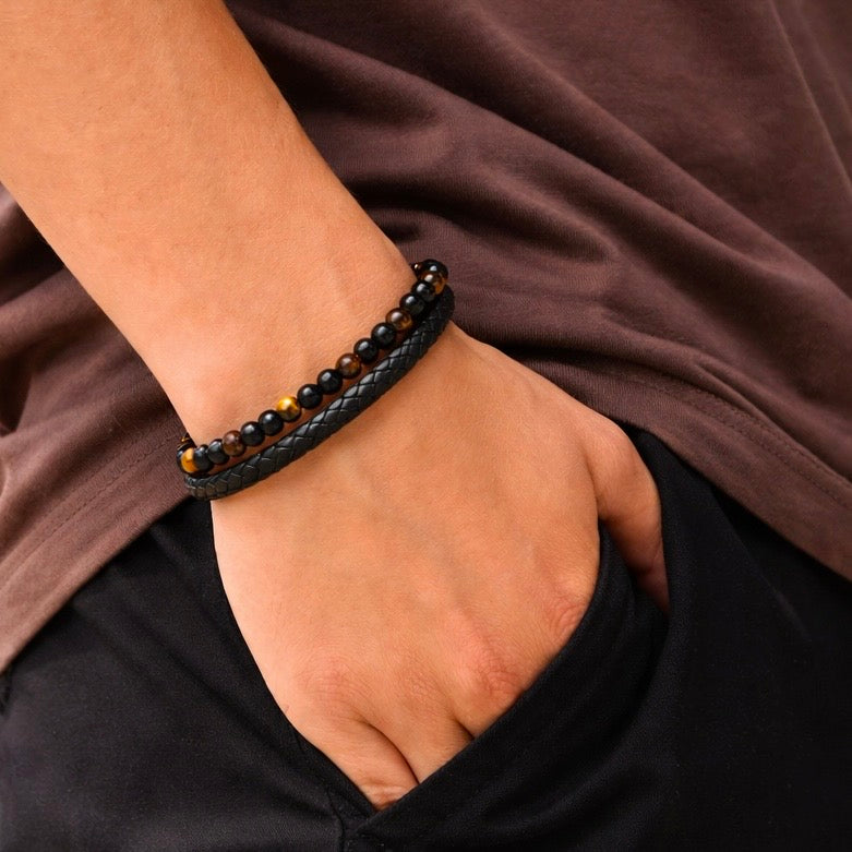 Close-up of the golden-brown and black beaded bracelet with a braided band on a man's wrist