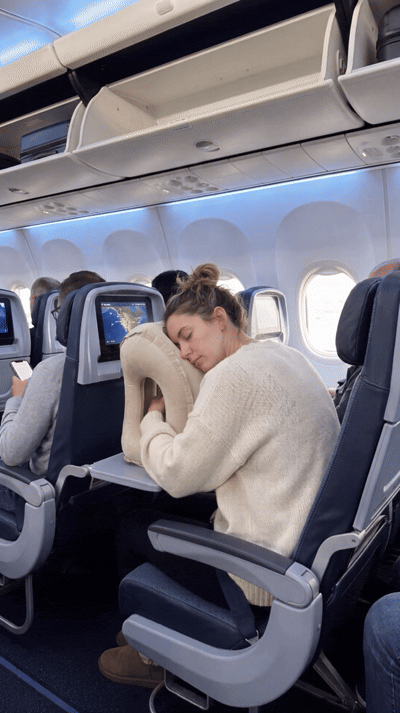 Traveler resting forward with a sleep pillow on an airplane