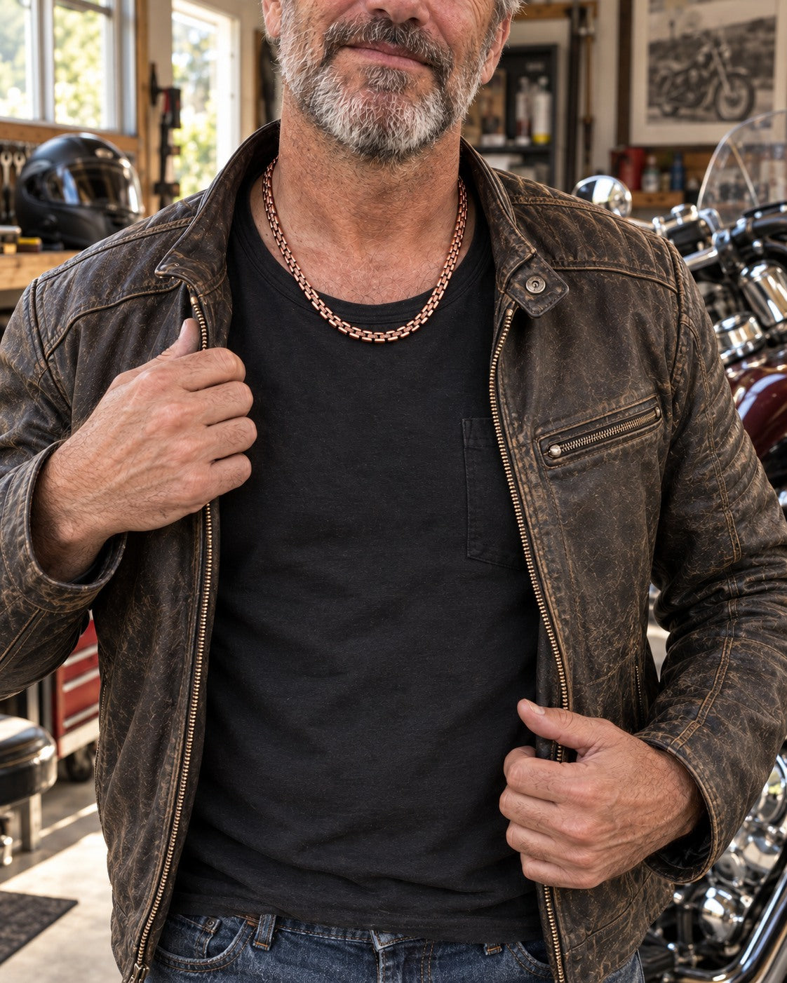 Man opening his riding jacket to show the copper necklace over a dark shirt